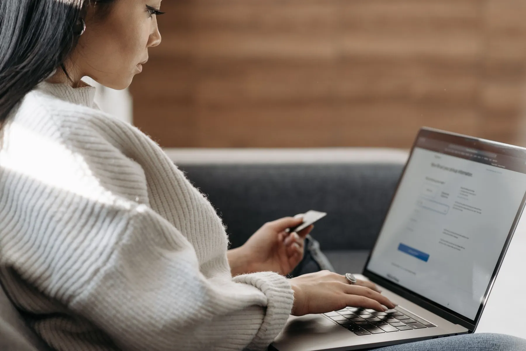 Person completing an online payment with a bank card and laptop